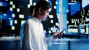 Asian man strolling around city streets at night, using smartphone to do online shopping, looking at clothes. Carefree person enjoying walking in empty metropolitan environment, using mobile phone photo