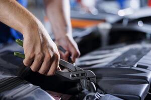 Car service technician expertly examines engine using advanced mechanical tools, ensuring ideal automotive performance and safety. Meticulous garage expert conducts routine vehicle checkup with pliers photo