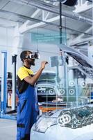 BIPOC mechanic in repair shop using augmented reality holograms to check car performance parameters during maintenance. Qualified garage employee using futuristic vr headset to examine damaged vehicle photo