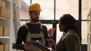 Proficient coworkers performing warehouse inventory controls, discussing ways of keeping quality standards high. Qualified experts preparing to ship parcels to customers, crosschecking delivery info photo