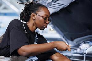 Repair shop technician examines damaged car motor using advanced mechanical tools, ensuring peak automotive performance. Proactive worker in garage workplace conducts routine vehicle checkup photo