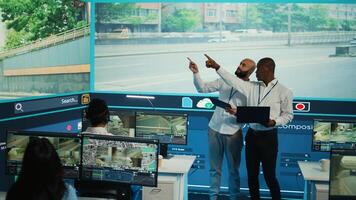 Diverse employees using CCTV surveillance system in monitoring traffic, tracking speed limits for public safety via satellite radar system. People operating on a big screen in control center. Camera B. photo