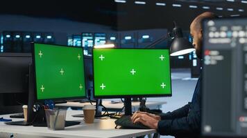Developer programming on multi monitor isolated screen PC setup in data center housing supercomputers storing datasets. Programmer writing code on chroma key computer to mend data center racks photo