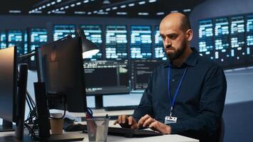 System operator overseeing server room, typing code on desktop PC, troubleshooting rigs. Software specialist doing maintenance on hardware clusters, networking systems and storage arrays photo