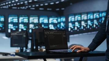 IT support employee writing code on laptop in high tech facility with server rows providing computing resources for different workloads. System administrator uses notebook to oversee supercomputers photo