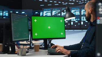 IT employee programming on green screen PC in data center housing supercomputers storing datasets. Admin writing code on mockup computer monitor to mend data center racks photo