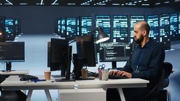 Computer scientist in server farm coding, ensuring data remains shielded from threats. IT programmer safeguarding supercomputers against unauthorized access, securing system from virus attacks photo