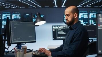 Software developer programming in high tech facility with server rows providing computing resources for different workloads. IT expert reviewing data center supercomputers photo