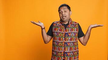 Indian man shrugging shoulders, unable to provide answer, having detached apathy facial expression. Apathetic person doing hand gesturing showing lack of knowledge, studio background, camera B photo