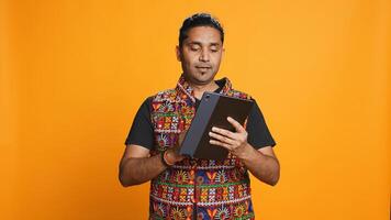 Man shakes head in disbelief after realizing lack of necessary funds while trying to shop online on tablet. Disappointed indian person gets credit card transaction rejected, studio backdrop, camera B photo