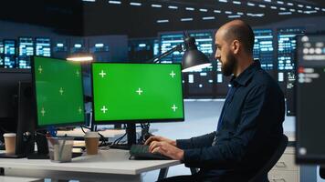 IT supervisor working on isolated screen computers in data center, ensuring optimal performance. Person monitoring energy consumption across servers with chroma key desktop PC photo