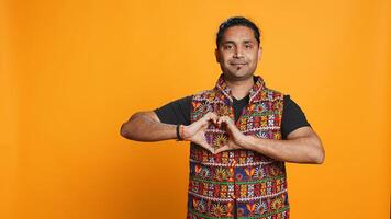 Portrait of jolly friendly indian man doing heart symbol shape gesture with hands. Cheerful nurturing person showing love gesturing, isolated over studio background, camera B photo