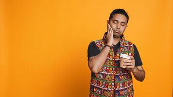 Sleepy man yawning and rubbing eyes. sipping coffee to wake up and gain energy. Exhausted person feeling fatigued after sleepless night, drinking caffeinated beverage, studio backdrop, camera B photo