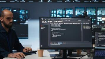 Engineer writing code in high tech facility with server rows providing computing resources for different workloads. Trucking right shot of employee overseeing supercomputers operating data photo