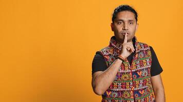 Authoritative man doing shushing hand gesturing, demanding secrecy, irritated by noise. Stern person complaining, placing finger on lips, doing quiet warning sign gesture, studio background, camera A photo