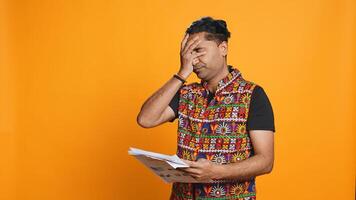 Irked manager looking over company financial profit report audit, disappointed by results, isolated over studio background. Mad indian man throwing business documents in frustration, camera B photo