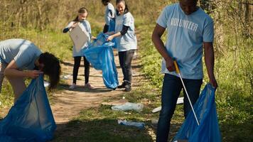eco simpático activista agarrando basura y el plastico residuos desde un bosque área, limpieza arriba el bosque y coleccionar basura en un basura bolsa. hombre voluntario relación comercial con residuos gestión. cámara una. foto
