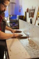 Carpenter puts wood block through spindle moulder wearing safety glasses to avoid injury. Cabinetmaker using heavy machinery to craft furniture using protective gear to prevent accidents photo