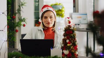 cerca arriba retrato de contable en Navidad decorado oficina comprobación documentos para exactitud. empleado resolviendo Tareas a computadora escritorio en Navidad florido espacio de trabajo durante invierno fiesta temporada foto