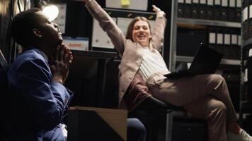Diverse team of exhausted private investigators in incident room analyze evidence, review files, and conduct research to solve case. Two detectives feeling tired about criminal investigation reports. photo