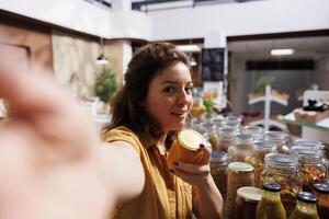 Content creator using selfie camera to make for social media channels, presenting newly opened zero waste store. Vlogger filming herself inside bulk products local neighborhood supermarket photo