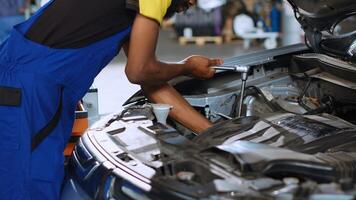 Meticulous mechanic in car service uses wrench to tighten screws after fixing vehicle parts. Repair shop employee utilizing professional tools to make sure automobile is operating flawlessly, close up photo