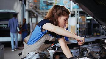 Precise worker in repair shop using torque wrench to tighten bolts after checking car performance during maintenance. Expert using professional tool in garage to fix automobile, close up photo