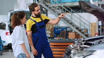 Mechanic in car service using augmented technology hologram to show woman automobile reaction to road conditions after fixing it. Repairman using AR technology with client to test vehicle engine photo