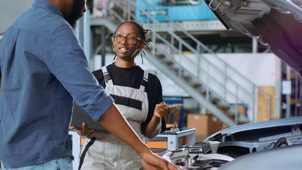 Engineer in car service using laptop to calculate repairments invoice for client after fixing malfunctions. Qualified specialist using device to determine final costs after servicing vehicle photo