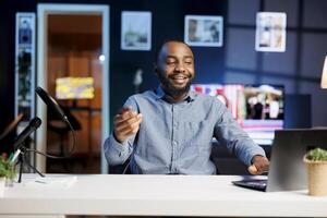 African american gamer playing games on livestream with fans watching, using powerful gaming laptop. Streamer using computer device to play videogames requested by subscribers photo