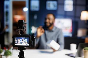 Focus on professional production camera used for capturing footage of content creator in blurry background doing products unboxing for online audience, showcasing different tech electronics photo