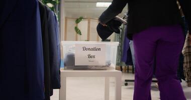Customers donating stylish formal clothes in thrift shop, doing good deed. Generous clients adding their garments in donation box for charitable event organized by SH clothing store photo