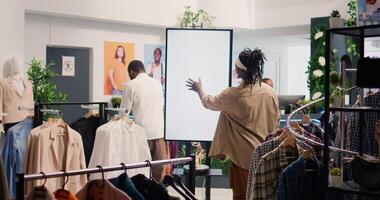 Man in shopping center fashion boutique using high tech screen to look at clothes options to try on. Client using led panel to visualize outfit combinations in store before buying, ground level shot photo