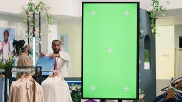 Second hand clothing shop green screen kiosk ready to be used by clients to choose between clothes. Chroma key digital display in thrift shop showcasing available garments sizes photo