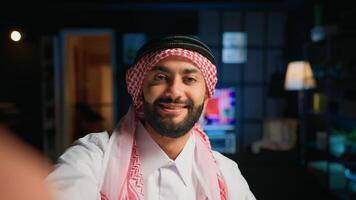 Point of view shot of arab content creator using smartphone to do live broadcast for subscribers, showing his home studio. Middle Eastern online star films himself using cellphone camera, POV photo