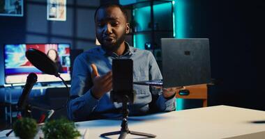 Media star films tech review of newly launched laptop, unboxing it and presenting specs to audience. Influencer showing notebook to fans, offering feedback of its performance, handheld camera shot photo