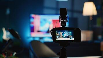 Extreme close up shot of camera on tripod used by media star in dimly lit apartment studio to film for online platforms. Recording device in empty room used by content creator to capture footage photo