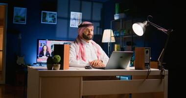 Arabic job candidate remotely being interviewed by human resources team while at home. Smiling muslim man getting his credentials checked during online conference meeting before being employed photo