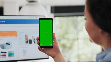 Worker checking greenscreen display on smartphone, holding device with copyspace blank software in coworking space. Woman working with isolated mockup display in agency office. Close up. photo