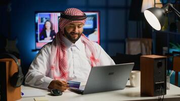 Arabic man doing online shopping, carefully typing credit card information on computer. Muslim person adding payment method on website while in cozy stylish warm home at night photo