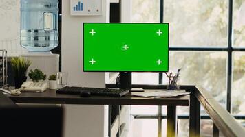 Modern coworking space with monitor showing isolated greenscreen, blank chromakey screen on computer. Empty office desk with pc running mockup template, copyspace layout on desktop. photo