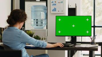 Businesswoman working at computer running isolated mockup display, sitting at office desk during work program. Employee using modern monitor with greenscreen copyspace layout at job. photo