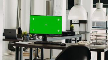 Greenscreen monitor in coworking space running on desk, open floor plan small business office. Computer showing isolated mockup template with blank chromakey screen, modern career. photo