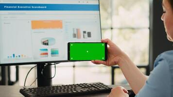 Businesswoman analyzing smartphone app with greenscreen template in startup coworking space. Person looking at isolated chromakey display with mockup on digital mobile device, copyspace. photo