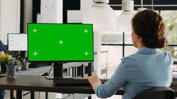 Manager working with isolated greenscreen on computer at workstation, looking at chromakey display with mockup template on desk. Businesswoman using pc in coworking space. photo