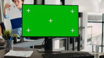 Greenscreen on computer desktop at empty workstation. PC with isolated mockup template and chromakey app running in open floor plan agency workplace, blank display copyspace technology. photo
