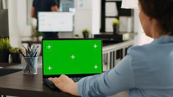 Business person using chromakey laptop with greenscreen template in startup office. Company employee looking at mockup copyspace with isolated mockup on wireless computer screen. photo