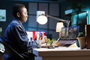 African American woman working from home, using laptop for virtual meeting with colleagues. Female freelancer engaged in online conference call, discussing and communicating remotely. photo