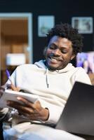 Entrepreneur working from home, writing down company ideas while watching internet . Man feeling enthusiastic after coming up with startup proposal, using pen to note strategy plan photo