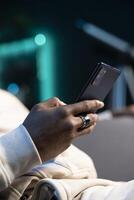 Close up shot on smartphone held by person sending messages to internet mates, enjoying himself at home. Focus on phone used by man in blurry background to catch up with friends photo